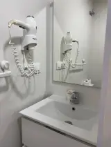 Baño completo de la Habitación Individual con inodoro, lavabo, espejo y ducha con tapete gris
